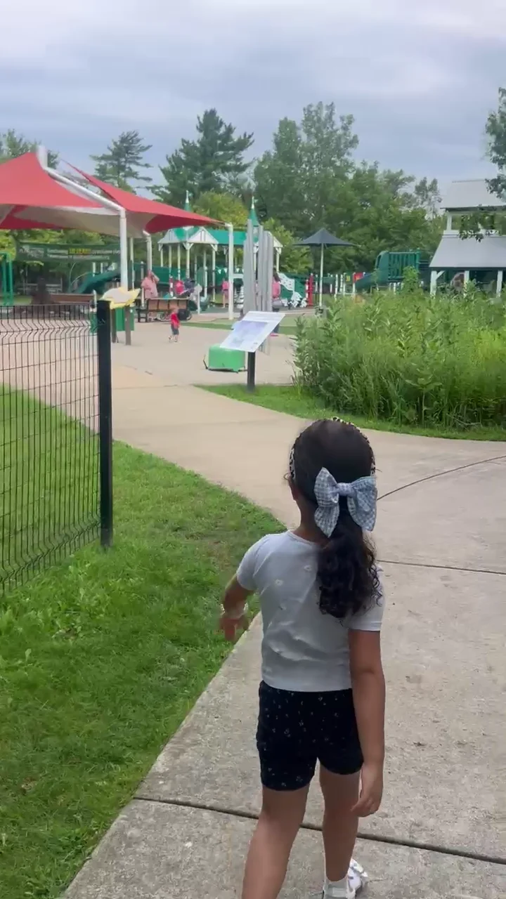 Kim’s daughter walking toward a colorful playground on one of their family trips.