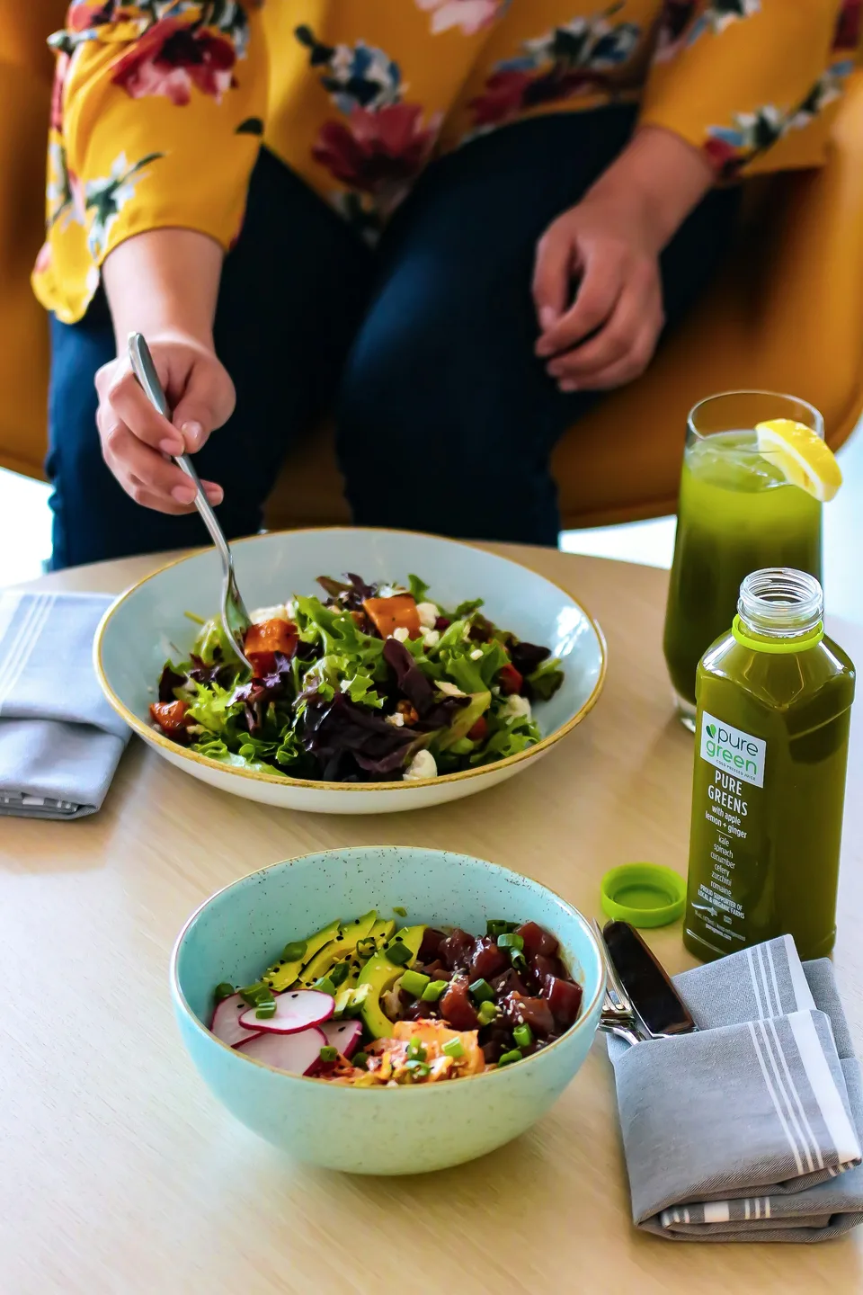 Colorful food bowls and pressed green juice on a table; illustrative marketing photograph.